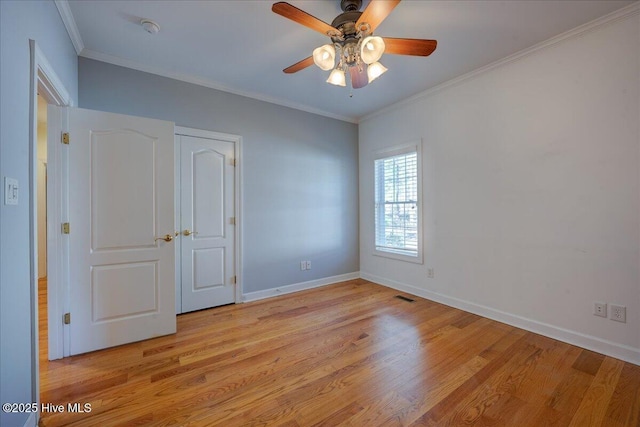 empty room with light wood-style floors, a ceiling fan, baseboards, and ornamental molding