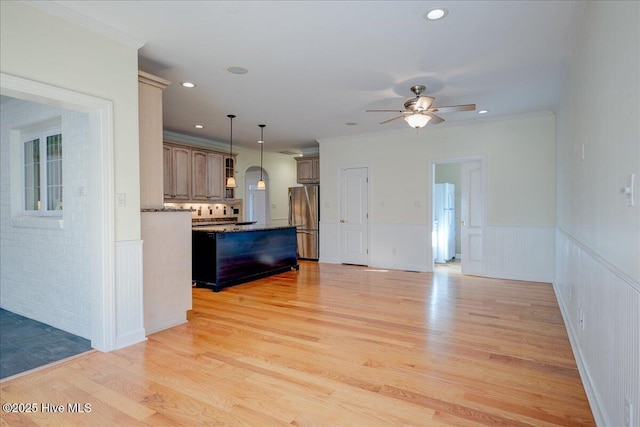 kitchen featuring crown molding, light wood-style floors, freestanding refrigerator, wainscoting, and a kitchen island