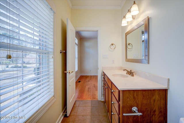 bathroom with tile patterned floors, baseboards, crown molding, and vanity