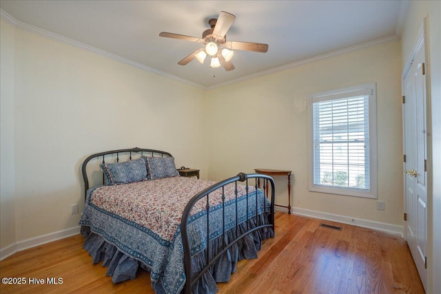 bedroom featuring baseboards, visible vents, wood finished floors, and ornamental molding