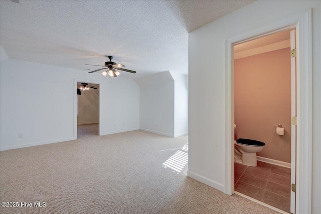 interior space with carpet floors, ceiling fan, baseboards, and a textured ceiling