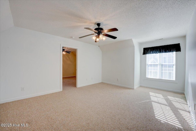 empty room featuring a ceiling fan, light colored carpet, a textured ceiling, and baseboards