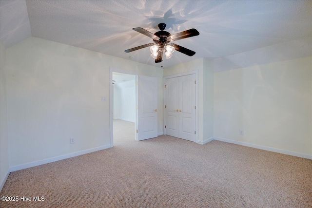 unfurnished bedroom with a closet, light carpet, ceiling fan, a textured ceiling, and baseboards