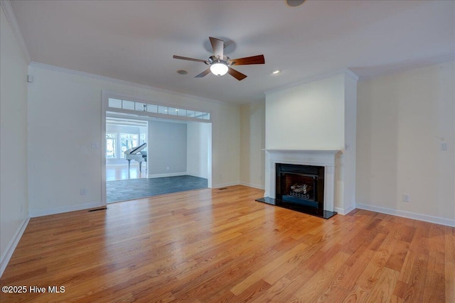 unfurnished living room featuring baseboards, a fireplace with raised hearth, a ceiling fan, light wood-style flooring, and crown molding