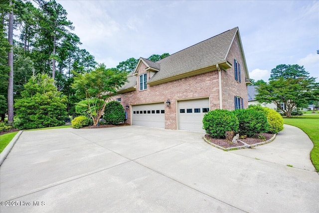 view of side of property featuring concrete driveway, brick siding, and roof with shingles