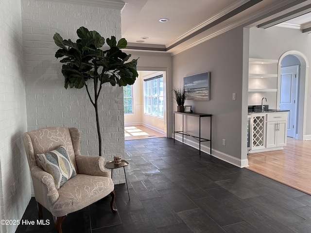 sitting room with indoor bar, dark wood-style flooring, baseboards, and ornamental molding