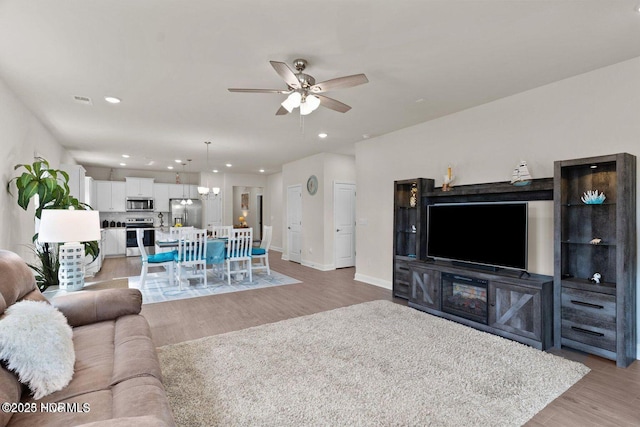 living area featuring light wood-style flooring, baseboards, a ceiling fan, and recessed lighting