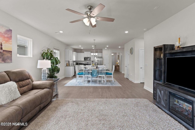 living area with baseboards, light wood finished floors, a ceiling fan, and recessed lighting