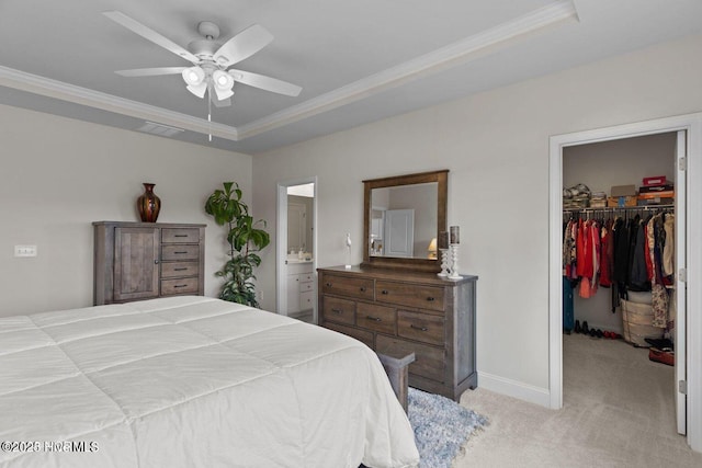 bedroom featuring light carpet, a spacious closet, ornamental molding, a closet, and a raised ceiling