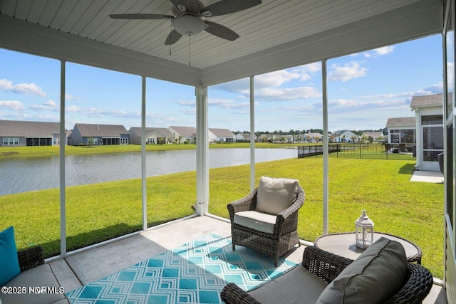 sunroom featuring a ceiling fan, a residential view, and a water view