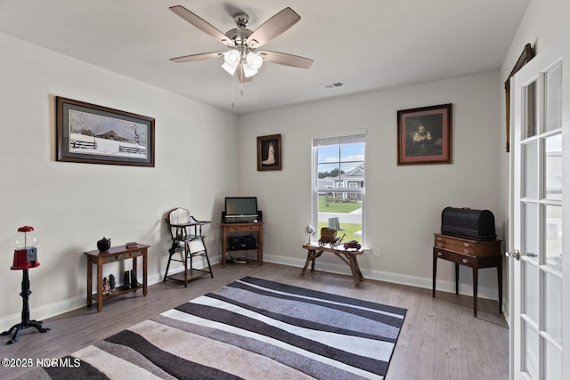 living area with a ceiling fan, baseboards, visible vents, and wood finished floors