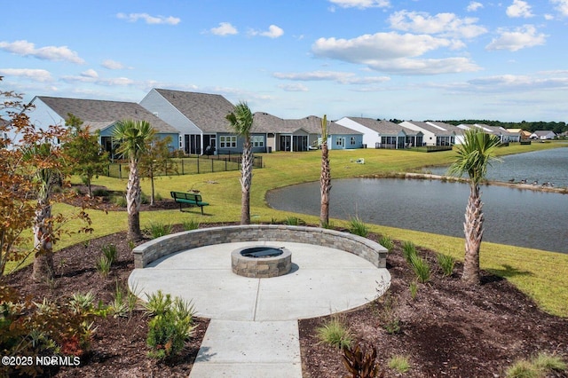 view of property's community with a yard, a water view, an outdoor fire pit, fence, and a residential view