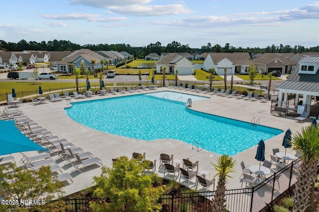 pool with a patio, a lawn, fence, and a residential view