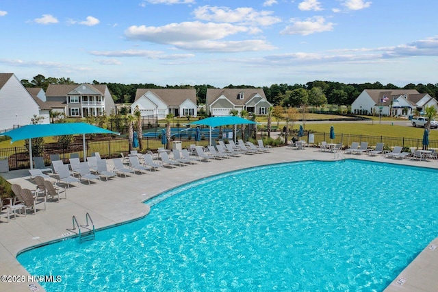 pool with a patio area, fence, and a residential view