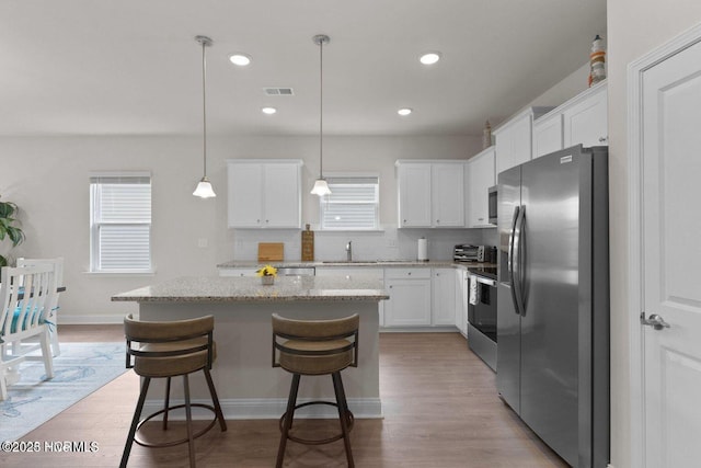 kitchen featuring light wood-style flooring, a kitchen island, visible vents, and stainless steel appliances