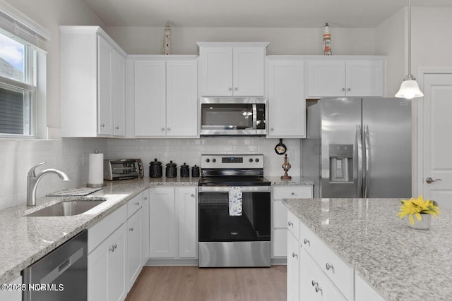 kitchen with appliances with stainless steel finishes, a sink, white cabinetry, and tasteful backsplash