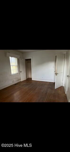 interior space featuring baseboards, dark wood finished floors, and a closet