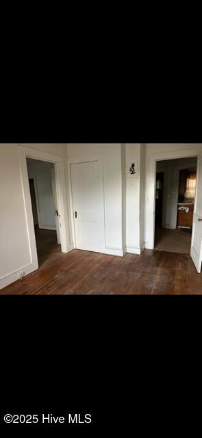unfurnished bedroom with a closet and dark wood finished floors