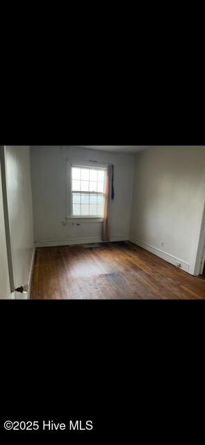 spare room with wood finished floors and baseboards