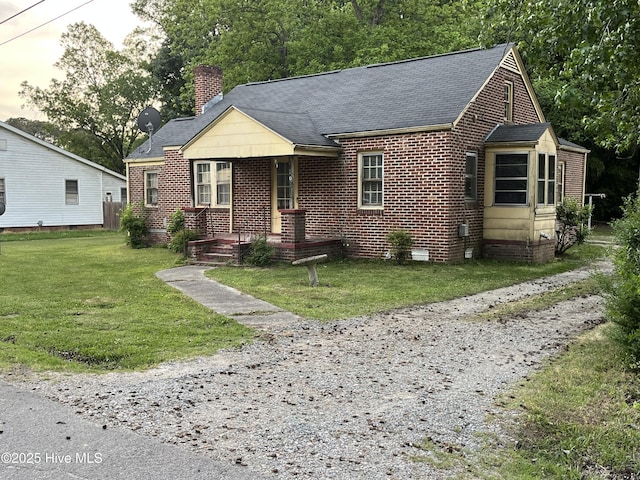 view of front of property with brick siding, a shingled roof, a front yard, and a chimney