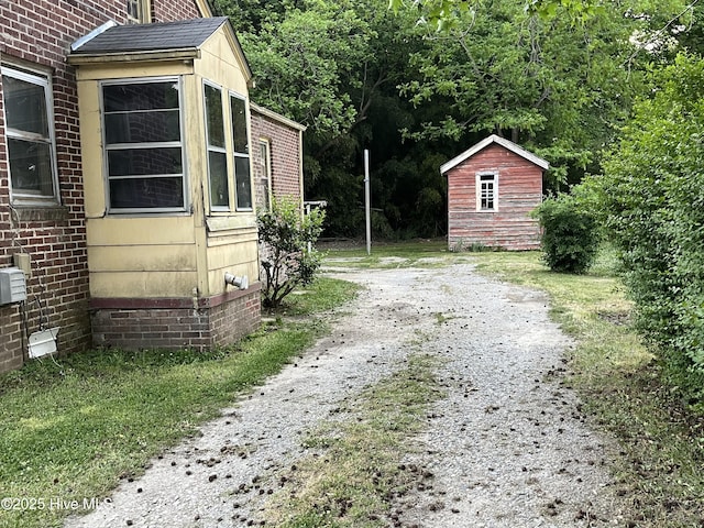 view of home's exterior featuring a shed, an outdoor structure, and dirt driveway