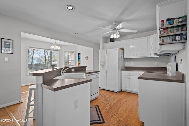 110 SE 7th St, Oak Island, NC 28465 - kitchen with white appliances, dark countertops, a center island with sink, a sink, and white cabinetry
