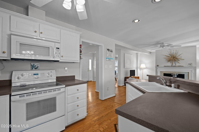 110 SE 7th St, Oak Island, NC 28465 - kitchen featuring white appliances, ceiling fan, a sink, dark countertops, and light wood-style floors