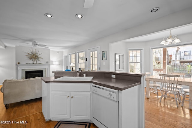 110 SE 7th St, Oak Island, NC 28465 - kitchen featuring dishwasher, a sink, dark countertops, ceiling fan, and light wood-style floors