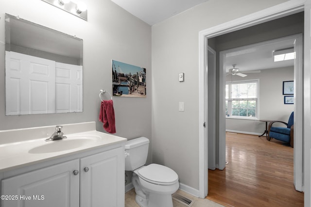 110 SE 7th St, Oak Island, NC 28465 - half bathroom with baseboards, toilet, vanity, wood finished floors, and ceiling fan