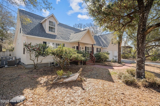 new england style home with a shingled roof and central air condition unit