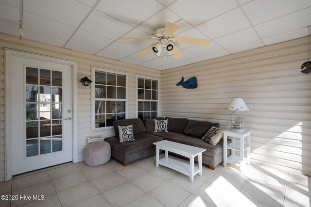 110 SE 7th St, Oak Island, NC 28465 - living area featuring a paneled ceiling, ceiling fan, tile patterned flooring, and wood walls