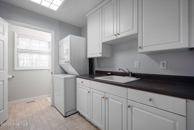 110 SE 7th St, Oak Island, NC 28465 - clothes washing area featuring estacked washer and dryer, cabinet space, and baseboards
