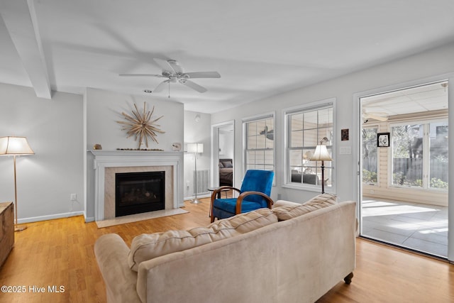 110 SE 7th St, Oak Island, NC 28465 - living area featuring a fireplace with flush hearth, light wood-type flooring, a ceiling fan, and baseboards