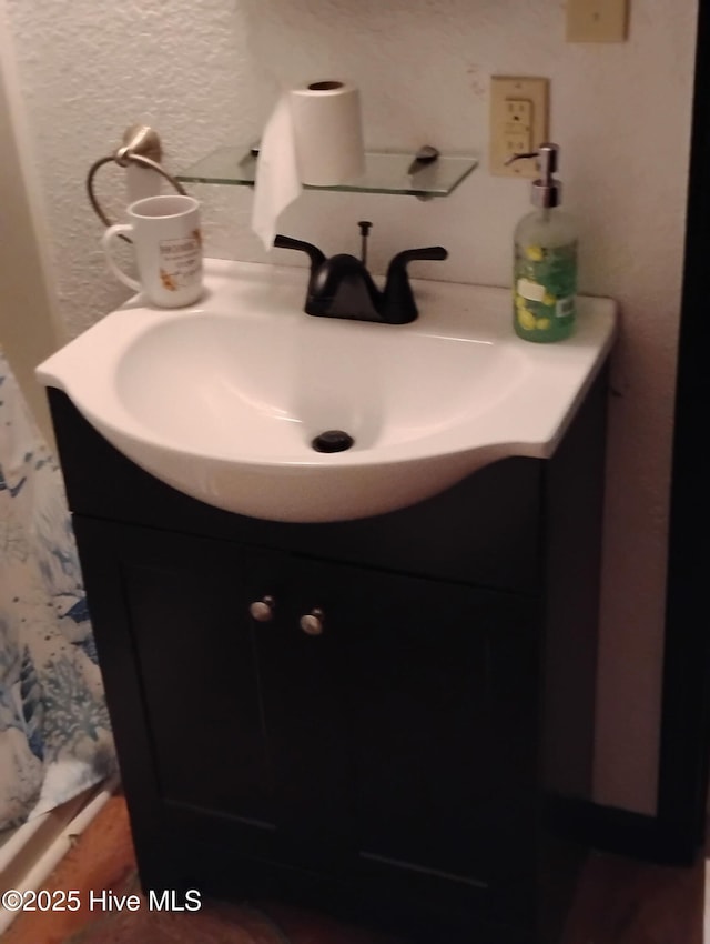 bathroom with a textured wall and vanity