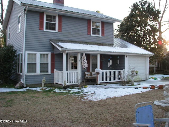 view of front facade with a garage, metal roof, a chimney, and a porch