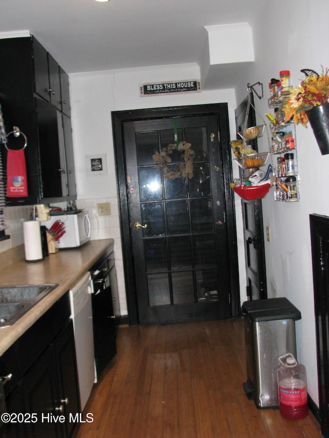 kitchen featuring dark wood-style floors, tile walls, white microwave, dark cabinets, and dishwasher