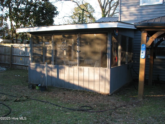 view of outbuilding with fence and a sunroom