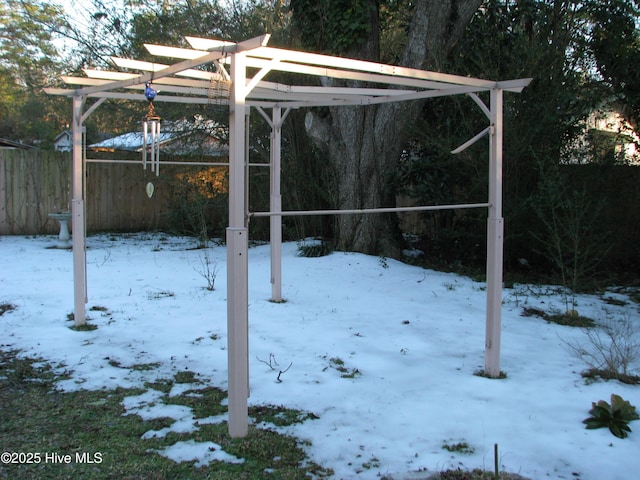 snowy yard with a carport and fence