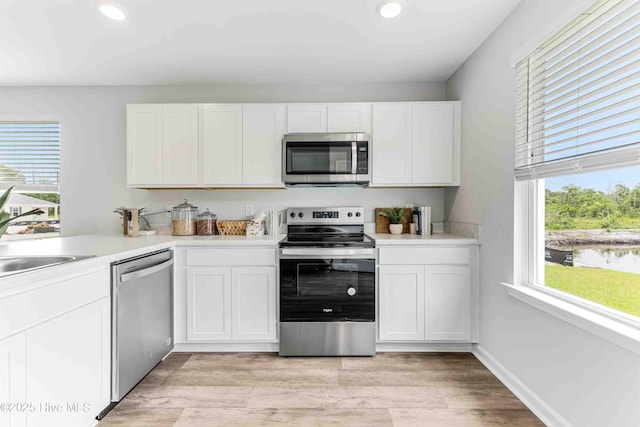 kitchen with appliances with stainless steel finishes, plenty of natural light, a sink, and white cabinetry