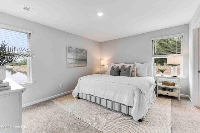 bedroom with carpet, visible vents, and multiple windows