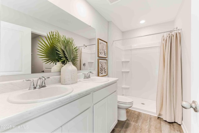 bathroom featuring wood finished floors, a sink, toilet, and a shower stall