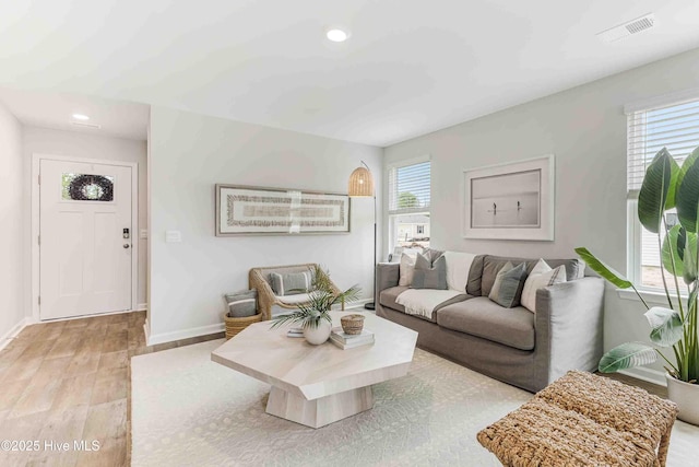 living area with recessed lighting, visible vents, baseboards, and wood finished floors