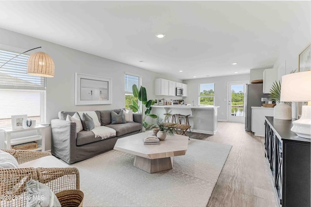 living area with light wood-type flooring, baseboards, and recessed lighting