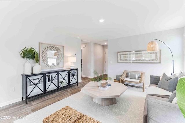 living area with baseboards, wood finished floors, and recessed lighting