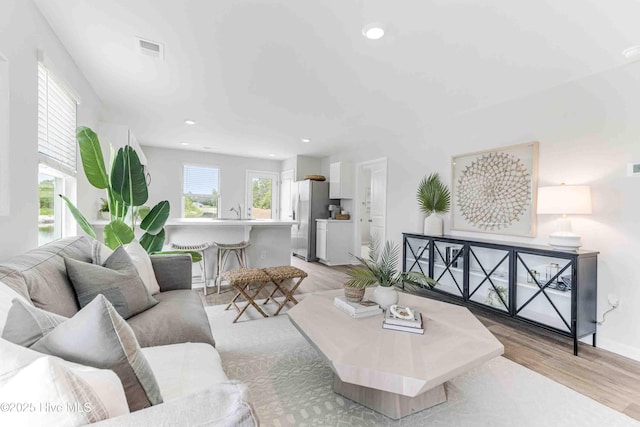 living area with light wood-style floors, visible vents, and recessed lighting