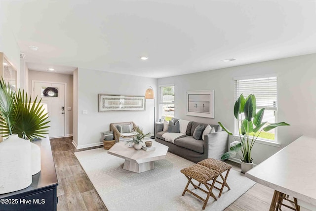 living area with baseboards, wood finished floors, and recessed lighting