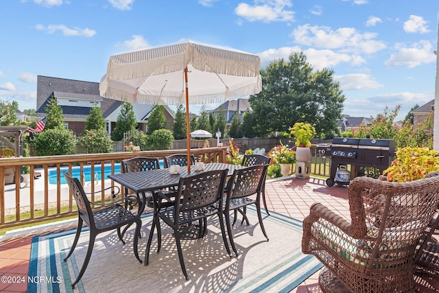 wooden terrace with outdoor dining area, fence, and a fenced in pool