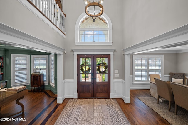 entryway featuring baseboards, wood finished floors, an inviting chandelier, a high ceiling, and french doors