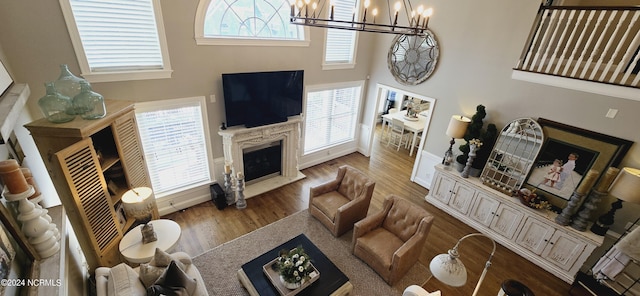 living area with a chandelier, wood finished floors, baseboards, and a premium fireplace