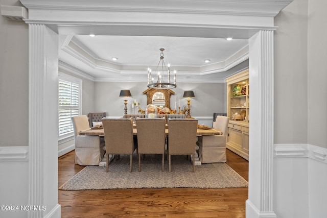 dining space featuring a chandelier, a tray ceiling, wood finished floors, and crown molding